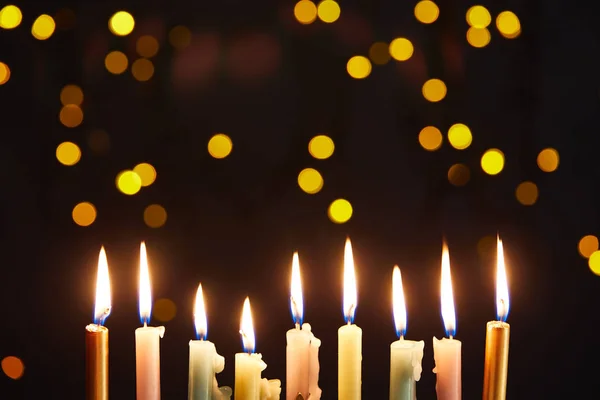 Glowing candles on black background with bokeh lights on Hanukkah — Stock Photo