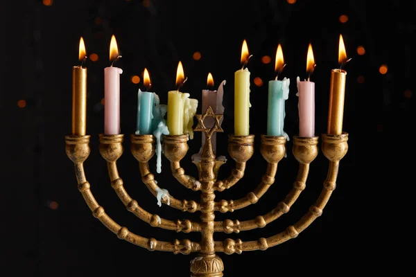 Velas brilhantes em menorah no fundo preto com luzes bokeh em Hanukkah — Fotografia de Stock