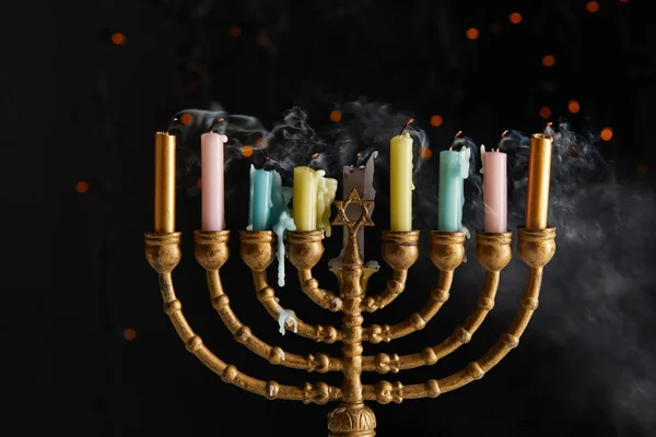 Velas en menorah con humo sobre fondo negro con luces bokeh en Hanukkah - foto de stock
