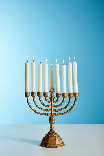 Velas encendidas en menorah sobre fondo azul - foto de stock