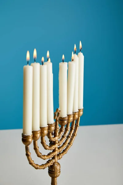 Velas encendidas en menorah aisladas en azul - foto de stock