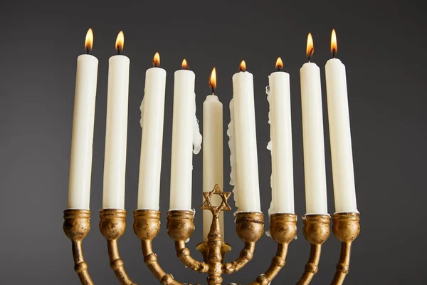 Vista en ángulo bajo de velas encendidas en menorah aisladas en gris - foto de stock