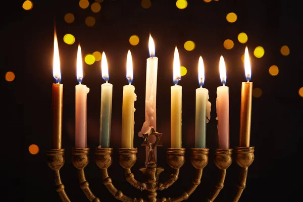 Burning candles in menorah on black background with bokeh lights on Hanukkah — Stock Photo