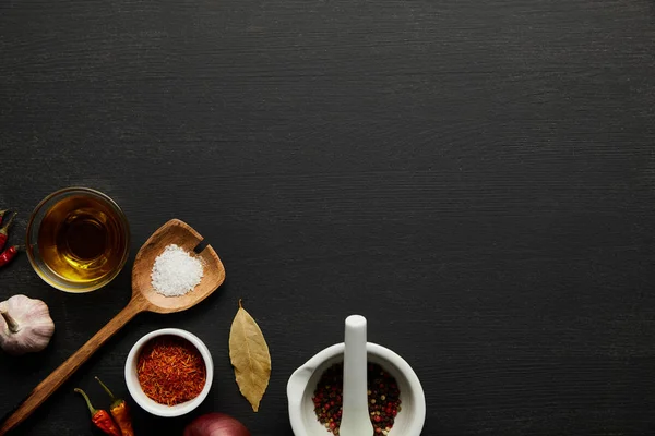 Ansicht von Gewürzen, Salz und Olivenöl auf schwarzem Holzhintergrund — Stockfoto