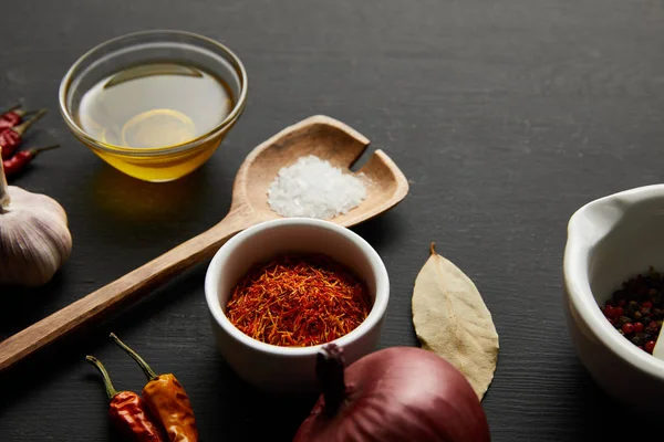 Chili peppers with salt, olive oil and onion on black wooden background — Stock Photo