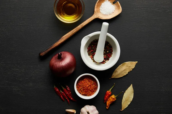 Top view of spices, olive oil with salt and bay leaves on black wooden background — Stock Photo