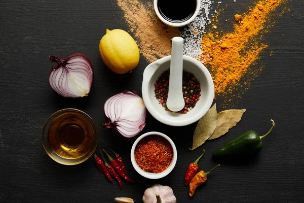 Top view of olive oil, soy sauce with lemon and spices on black wooden background — Stock Photo