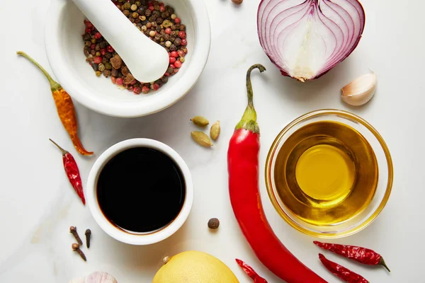 Draufsicht auf Zwiebeln, Sojasauce mit Chilischoten und Olivenöl auf Marmorhintergrund — Stockfoto