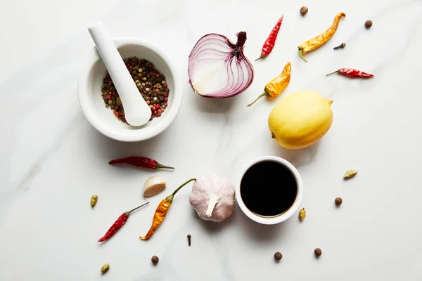 Vista superior de especias con salsa de soja, limón y cebolla sobre fondo de mármol - foto de stock