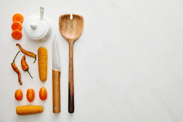 Vue de dessus de cuillère en bois avec couteau et légumes sur fond de marbre — Photo de stock