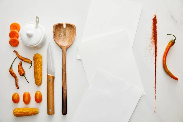 Vue de dessus des légumes avec cuillère en bois, couteau et blancs vides sur fond de marbre — Photo de stock