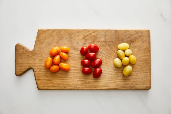 Top view of ripe cherry tomatoes on cutting board on marble background — Stock Photo