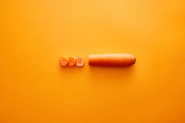 Top view of carrot with slices on orange background — Stock Photo