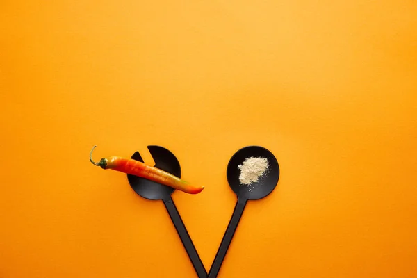 Geschirr mit Gewürzen und Chilipfeffer auf orangefarbenem Hintergrund von oben — Stockfoto