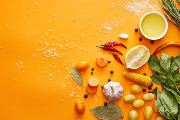 Вид сверху свежих овощей с зеленью и специями на оранжевом фоне — стоковое фото