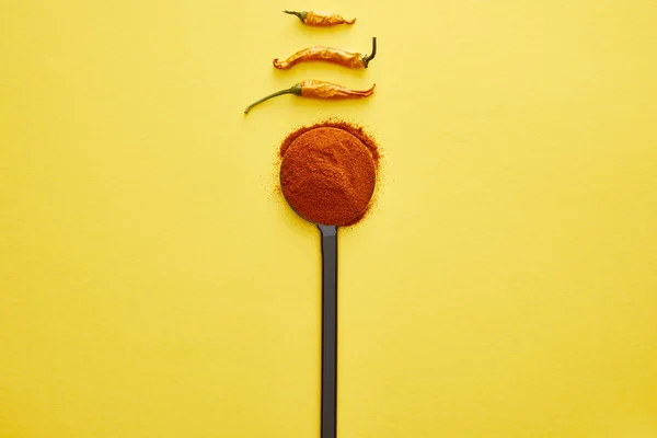 Top view of chili peppers and spice in spoon on yellow background — Stock Photo