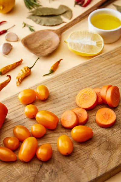 Selective focus of fresh vegetables on cutting board with spices and olive oil on beige background — Stock Photo