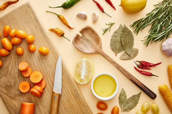 Top view of fresh vegetables on cutting board and spices on beige background — Stock Photo