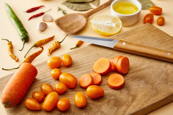 Enfoque selectivo de verduras orgánicas en la tabla de cortar y especias sobre fondo beige - foto de stock