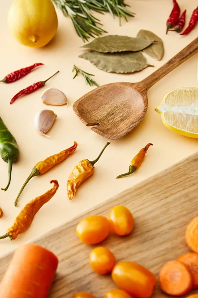Selective focus of organic vegetables on cutting board and chili peppers on beige background — Stock Photo