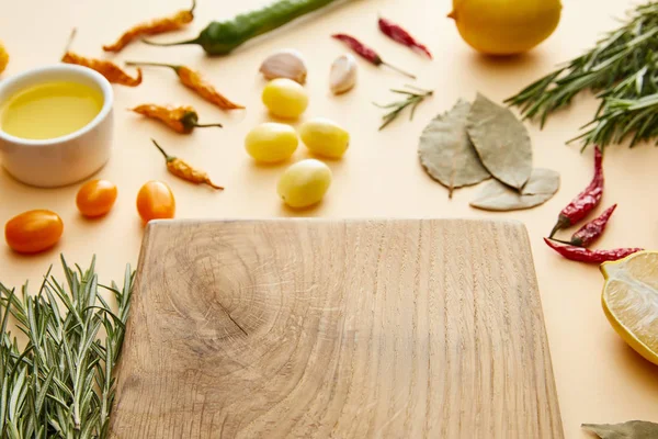 Foco seletivo da tábua de corte com legumes frescos e alecrim em fundo bege — Fotografia de Stock