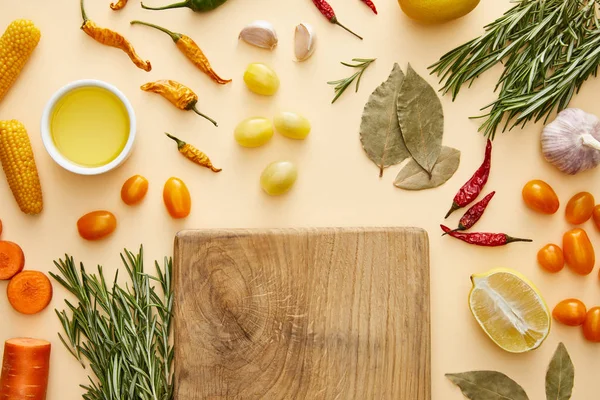 Top view of cutting board with fresh vegetables and rosemary on beige background — Stock Photo