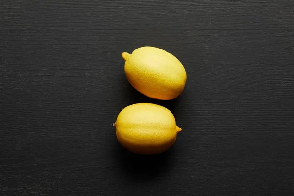 Top view of two fresh lemons on black wooden background — Stock Photo