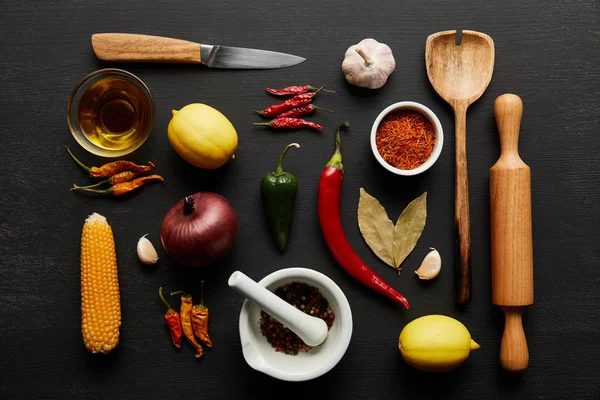 Vista superior de utensílios de cozinha com legumes orgânicos e especiarias em fundo de madeira preta — Fotografia de Stock