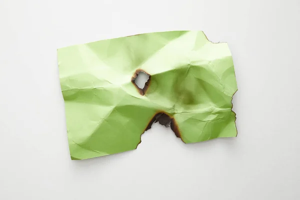 Vue du dessus du papier vert froissé et brûlé vide sur fond blanc — Photo de stock