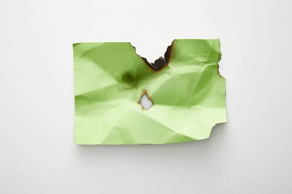 Vue du dessus du papier vert froissé et brûlé vide sur fond blanc — Photo de stock