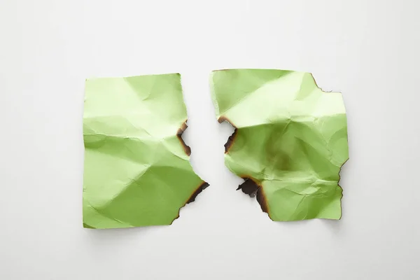 Draufsicht auf leeres zerknülltes, zerrissenes und verbranntes grünes Papier auf weißem Hintergrund — Stockfoto