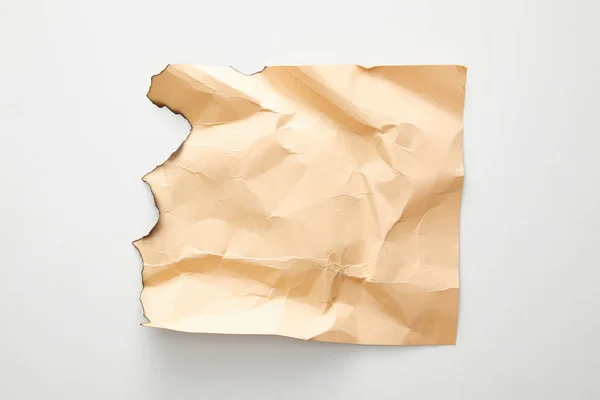 Draufsicht auf leeres zerknittertes und verbranntes beiges Altpapier auf weißem Hintergrund — Stockfoto