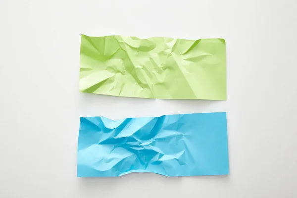 Vue du dessus du papier bleu et vert froissé vide sur fond blanc — Photo de stock