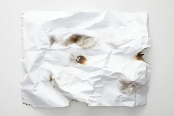 Vue du dessus du papier vintage froissé et brûlé vide sur fond blanc — Photo de stock