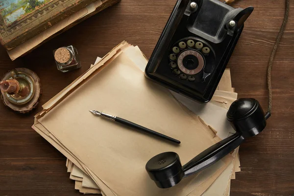 Top view of vintage paper, painting, fountain pen, candle and dial phone on wooden table — Stock Photo