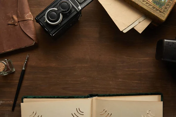 Vue du dessus de l'appareil photo vintage, album photo, peinture, stylo plume sur la table en bois — Photo de stock