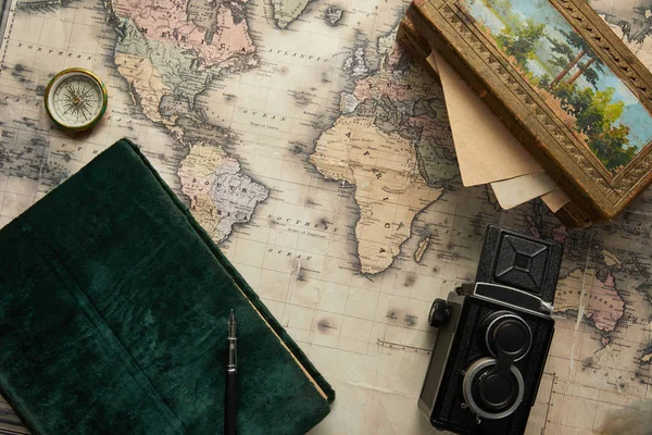 Top view of vintage camera, compass, fountain pen, photo album and painting on map background — Stock Photo