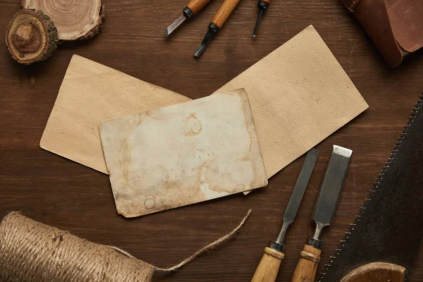 Верхний вид старых столярных инструментов рядом с чистыми старинными бумагами на деревянном столе — стоковое фото