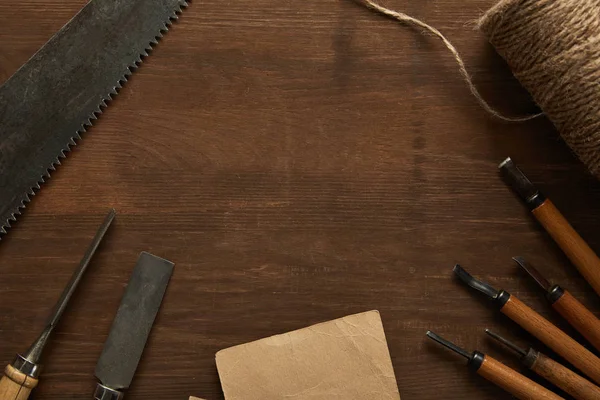 Top view of aged carpentry tools and twine near blank vintage paper on wooden table — Stock Photo