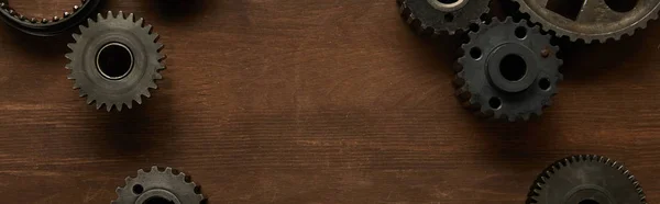 Top view of aged gears on wooden table, panoramic shot — Stock Photo