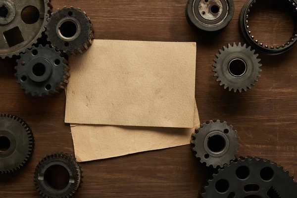 Top view of vintage paper and gears on wooden table — Stock Photo