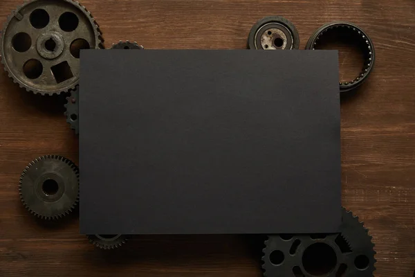 Vista superior de papel preto vintage e engrenagens na mesa de madeira — Fotografia de Stock