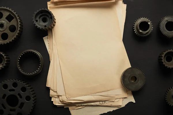 Ansicht von gealterten Zahnrädern und Altpapier auf schwarzer Oberfläche — Stockfoto