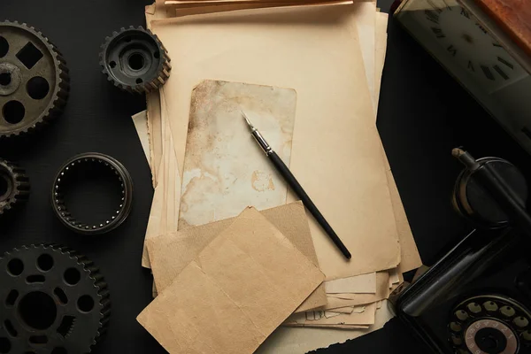 Vue de dessus des engrenages vieillis et du papier blanc vintage avec stylo plume sur la surface noire — Photo de stock