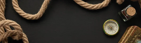 Top view of vintage paper, rope, compass and painting on black background, panoramic shot — Stock Photo