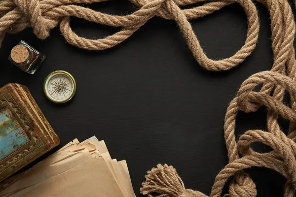 Top view of vintage paper, rope, compass and painting on black background — Stock Photo