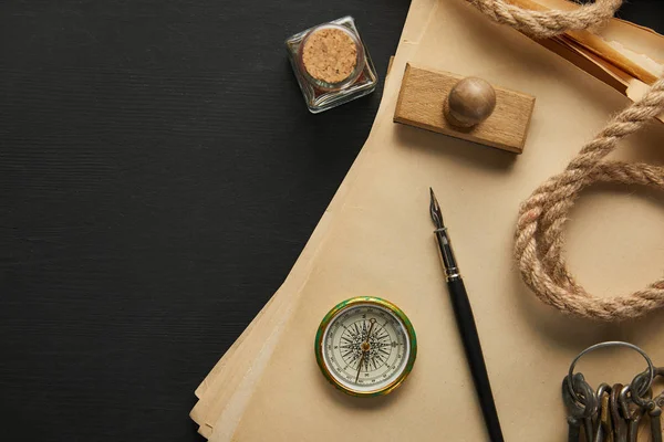 Top view of vintage paper, rope, compass, stamp, keys and fountain pen on black background — Stock Photo