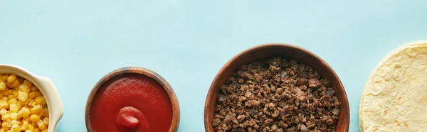 Top view of tortillas, minced meat with corn and ketchup on blue background, panoramic shot — Stock Photo