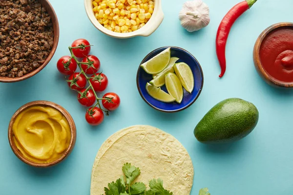 Tortillas frescas con ingredientes de taco, mostaza y salsa de tomate sobre fondo azul - foto de stock