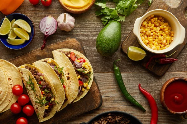Vista dall'alto dei tradizionali tacos messicani con ingredienti biologici su sfondo di legno — Foto stock